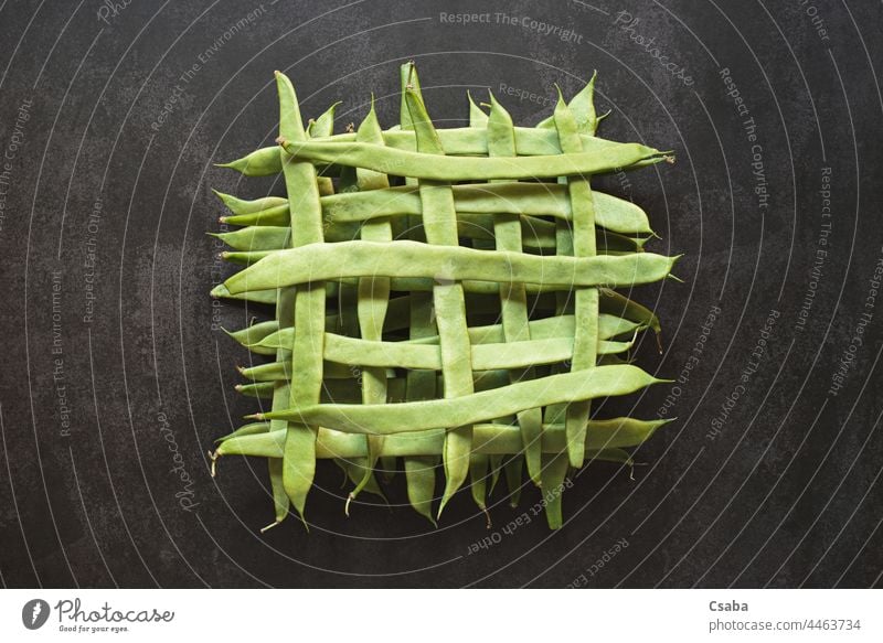 Draufsicht auf ganze grüne Bohnen in einem geometrischen Muster auf dunklem Hintergrund Form Vegetarier Gesundheit Lebensmittel Gemüse roh Bestandteil Veggie