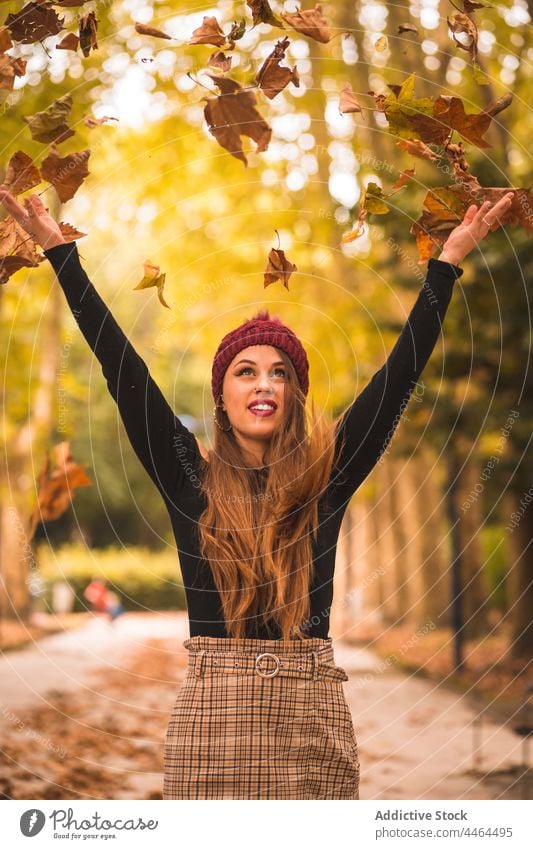 Lächelnde Frau wirft Herbstblätter im Park werfen Blatt trocknen Stil Haufen sorgenfrei Gasse Bewegung trendy Pflanze Laubwerk fallen Hand erhoben hochreichen