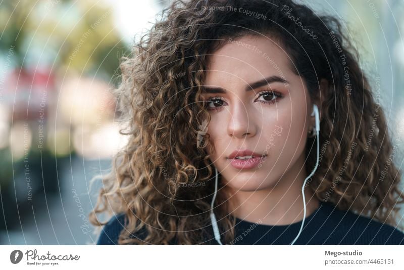 Junge lateinamerikanische Frau trägt Kopfhörer, während sie im Freien steht. Latein jung hören Straße urban Großstadt Lifestyle Drahtlos Ausdruck ernst