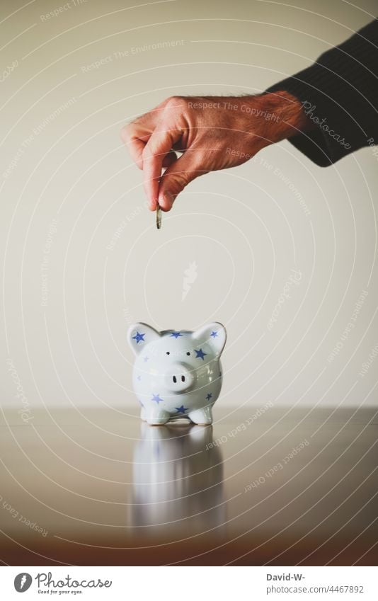Mann wirft einen Euro in ein Sparschwein - Konzept - sparen Spardose Zukunftsorientiert Geld sparsam Hand € Erfolg Geldmünze inflation