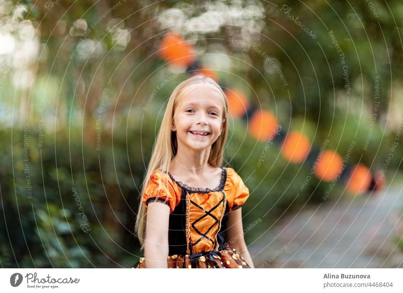 Kleine kaukasische Mädchen in Kostüm der orange und schwarze Farbe und feiern Halloween im Freien Hexe Tracht Hut Kind beängstigend Person Kürbis Kindheit