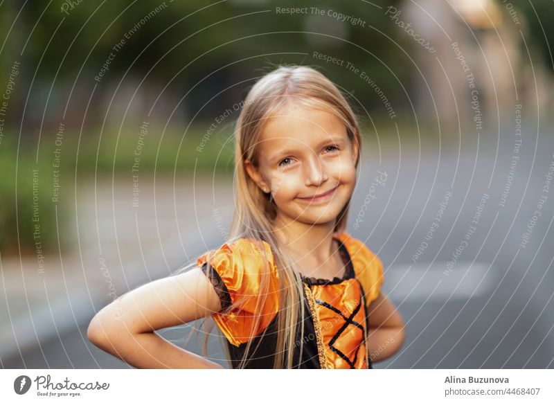 Kleine kaukasische Mädchen in Kostüm der orange und schwarze Farbe und feiern Halloween im Freien Hexe Tracht Hut Kind beängstigend Person Kürbis Kindheit