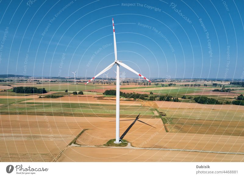 Windrad inmitten landwirtschaftlicher Felder. Windturbinengenerator an einem Sommertag. Windenergie-Konzept. Nachhaltige und erneuerbare Energie für den Klimaschutz. Grüne Energie