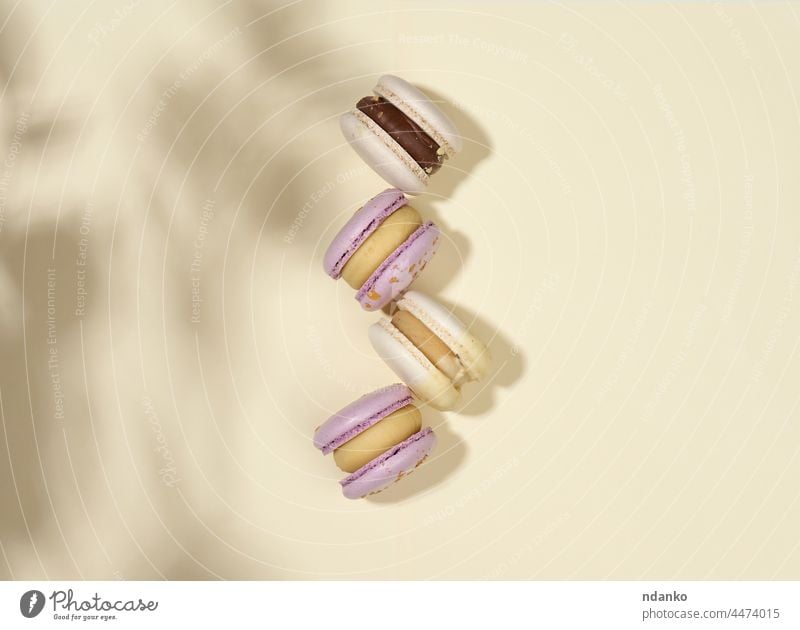 gebackene Macarons mit verschiedenen Geschmacksrichtungen auf beigem Hintergrund, Draufsicht Schatten Mandel sortiert Bäckerei Biskuit Kuchen Konfekt Konditorei