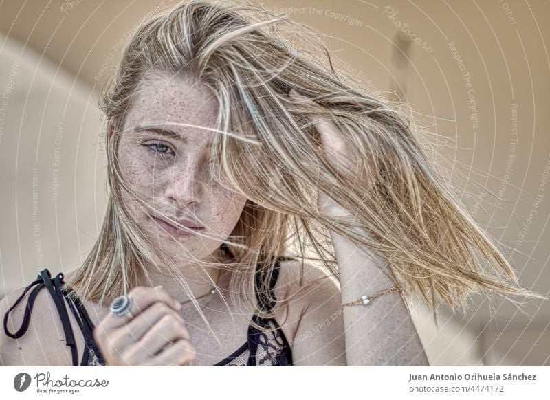 Junge blonde Frau mit sommersprossigem Gesicht und im Wind wehendem Haar freck sommersprossiges Gesicht Haare blasen Haare wehen im Wind hübsch grüne Augen