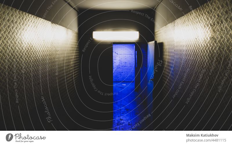 Blaues Licht hinter einer offenen Tür in einem geheimnisvollen Korridor. Geheimzugang blau Eingabe Gang Ausfahrt industriell Flucht Stahl Industrie Wand Metall