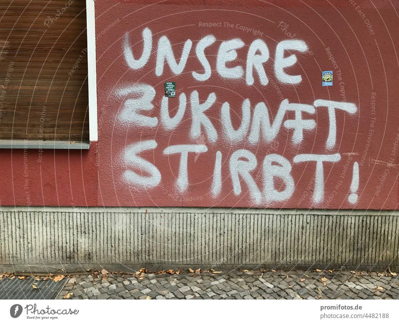 Graffiti auf roter Hauswand mit Fenster: "Unsere Zukunft stirbt!" / Foto: Alexander Hauk Wand silber geschlossen Außenaufnahme Tageslicht Gehweg Bürgersteig