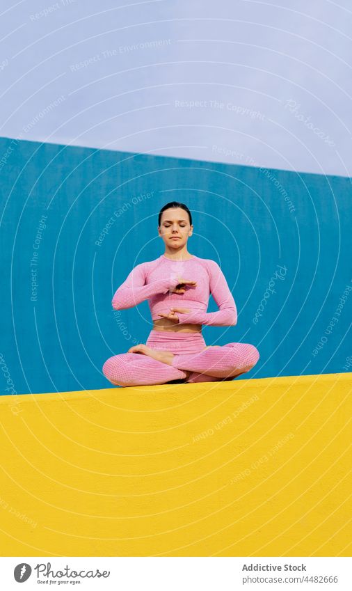 Ruhige Frau meditiert und macht Yoga in Lotus-Pose meditieren beweglich padmasana lebhaft farbenfroh Windstille Zen Stressabbau atmen üben Konzentration