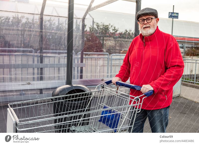 Senior, der einen Einkaufswagen schiebt Lächeln optimistisch in den Ruhestand getreten Großvater Karre Mann Verbraucher männlich Kunde Kaukasier Handwagen