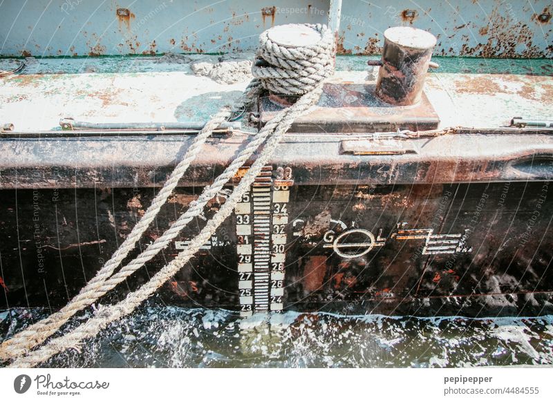 Immer eine Handbreit Wasser unterm Kiel – altes, rostiges Schiff im Hafen liegend und mit einem alten Tau befestigt Kielwasser Außenaufnahme Wasserfahrzeug