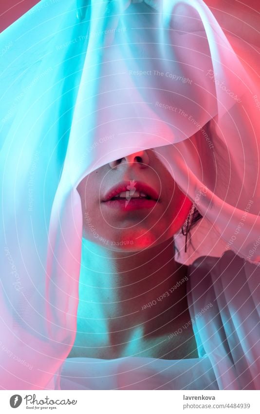 Studio-Porträt einer Frau mit neonblauen und roten Blitzen in den Augen bedeckt Stoff neonfarbig Model künstlerisch dunkel allein Hipster cool stylisch retro