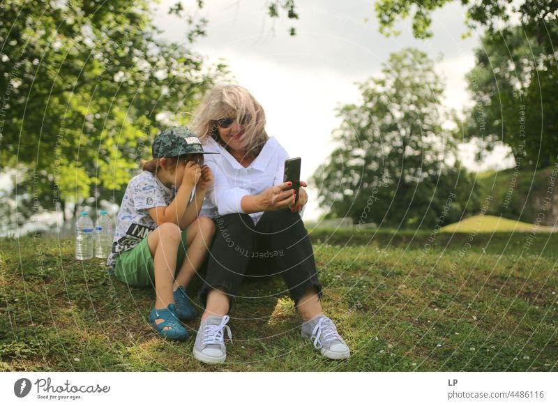 Mutter zeigt einem Kind etwas auf ihrem Handy Elternschaft Fokus Aufsicht Zusammengehörigkeitsgefühl Zusammensein Lehre Lehrer ernst einsiedlerisch Nachricht