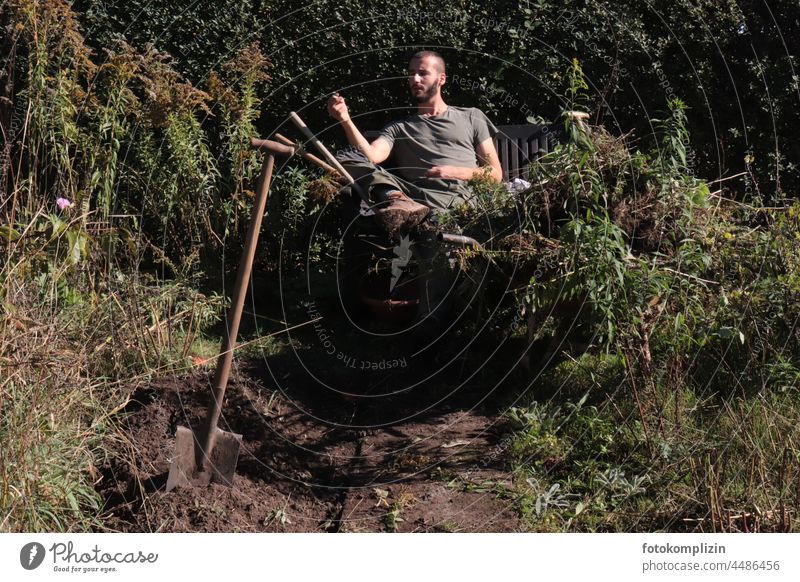 junger Gärtner macht Pause, nachdem er mit einem Spaten Erde umgegraben hat Gartenarbeit Mann gärtnern umgraben verblüht Herbst Herbstbeginn ausruhen