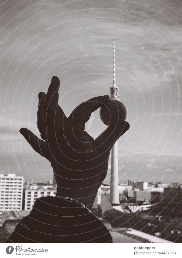 Golfball in einer Hand, die vor dem Berliner Fernsehturm gehalten wird Handarbeit Fernsehturm Berlin Alexanderplatz experimentell Experiment experimentieren