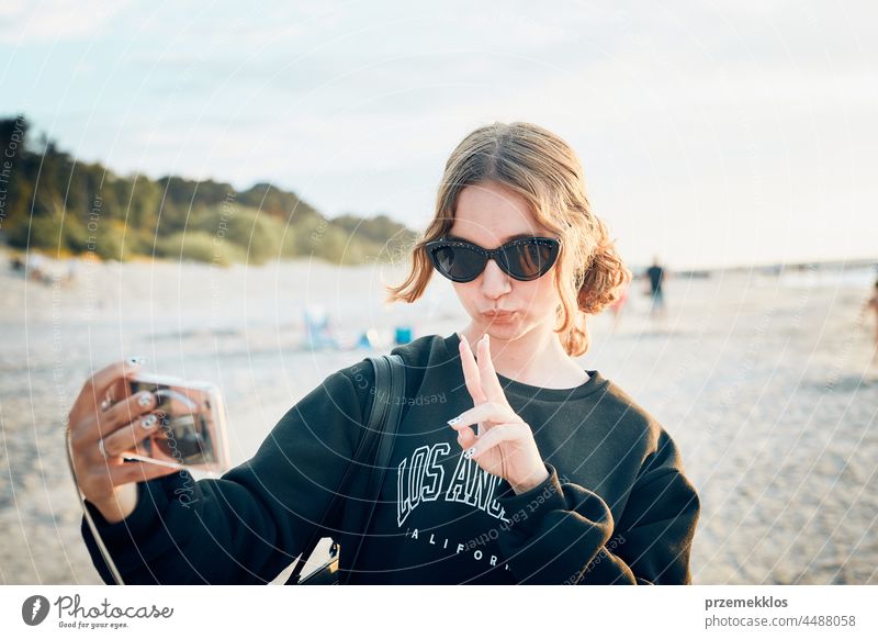 Teenager-Mädchen macht Geste während Videoanruf auf Smartphone während Reise in den Sommerferien Anruf Telefon Talkrunde gestikulieren Gruß unter Foto Selfie