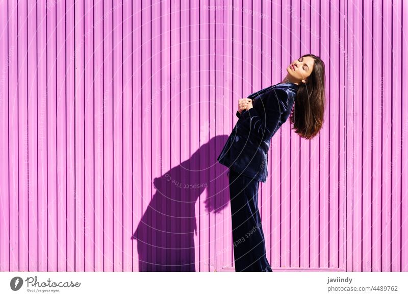 Frau in blauem Anzug posiert in der Nähe eines rosa Rollladens. Frisur Behaarung Mode Model Gebäude blind Fuchsie purpur bewegend Mädchen Person Lifestyle urban