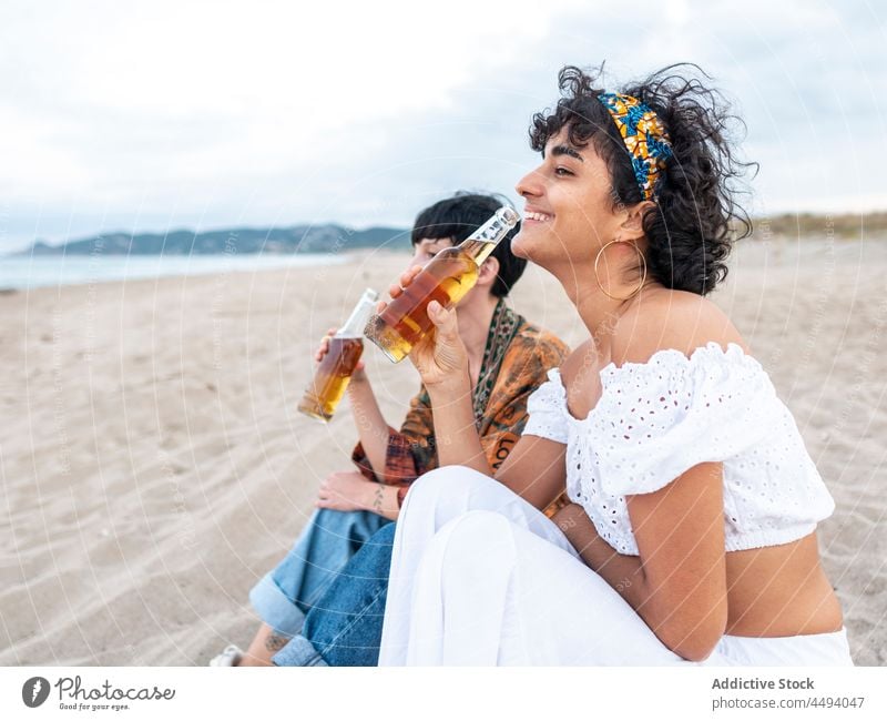 Glückliche Frauen trinken Bier am Strand Lachen Sommer Abend bester Freund Alkohol Zusammensein multiethnisch rassenübergreifend vielfältig Küste Meeresufer