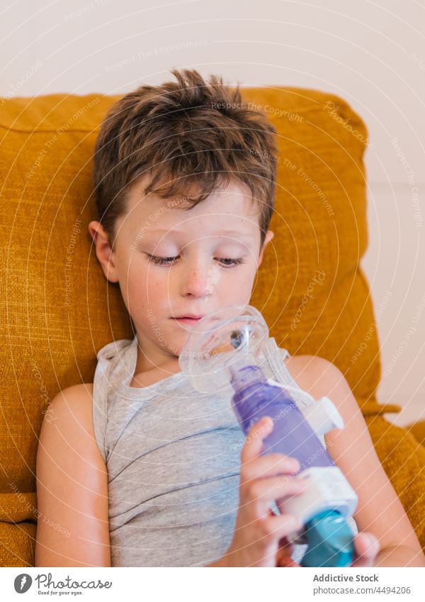 Krankes Kind, das mit einem Inhalator in einem Beatmungsgerät atmet Atemschutzgerät Atmung inhalieren atmen Mundschutz krank Pflege medizinisch Junge