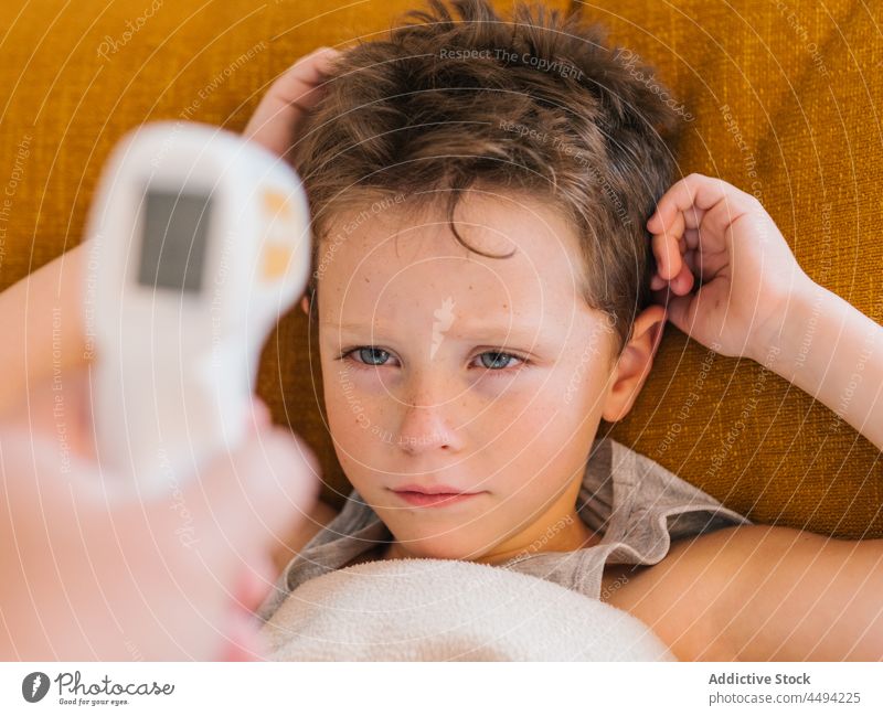 Eltern messen die Temperatur ihres Kindes mit einem Infrarotthermometer Infrarotaufnahme Thermometer krank Fieber heimwärts Decke Problematik prüfen untersuchen