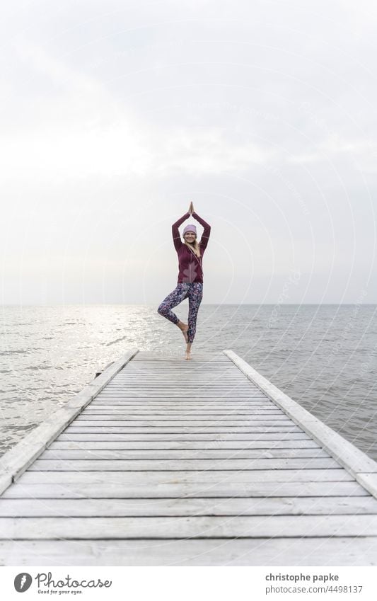 Frau in Sportbekleidung macht Yoga am Steg vor Meer Herbst See Fitness ufer Gesundheit Training sportlich Wellness Lifestyle Außenaufnahme Erwachsene Mensch