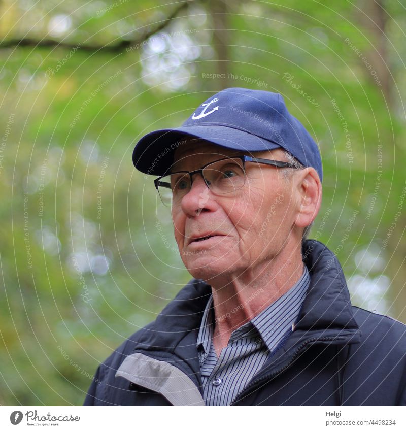 Porträt eines Senioren  mit Kappe, Brille und Jacke vor natürlichem unscharfen Hintergrund Mensch Mann draußen Natur Hemd Außenaufnahme maskulin Erwachsene