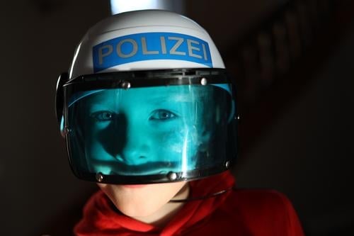 Junge spielt mit Polizeihelme und blauem Visier erschrecken Spiel Kinder Kindheit Spaß spielen Freizeit rot Freude verkleiden Verkleidung