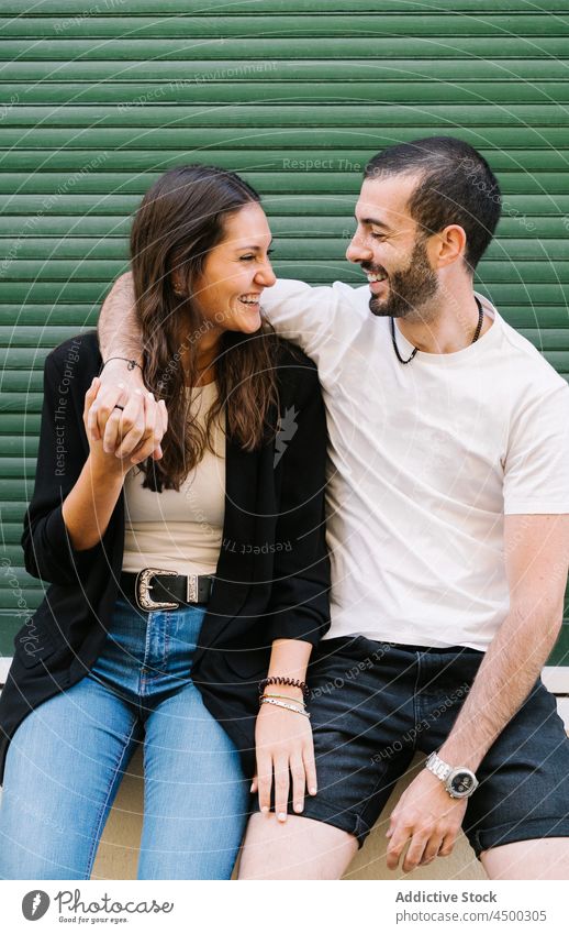 Fröhliches liebendes ethnisches Paar, das sich auf der Straße lächelnd ansieht Lachen Umarmung Liebe heiter Partnerschaft Zusammensein romantisch Glück