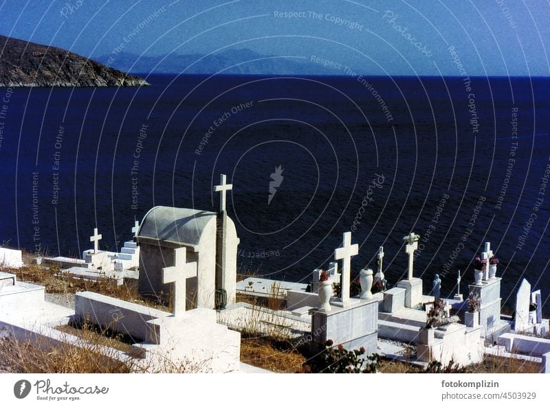 Blick auf das Meer von einem hohen Friedhof mit weißen Gräbern und Kreuzen auf dunkelblauem Wasser Grabsteine Tod Trauer Beerdigung Religion & Glaube