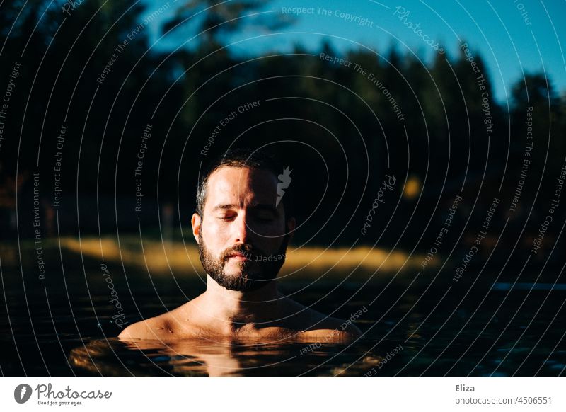 Mann mit geschlossenen Augen im Wasser bei Sonnenschein geschlossene Augen Entspannung baden draußen Erholung Natur Ruhe Meditation Erwachsener Landschaft See