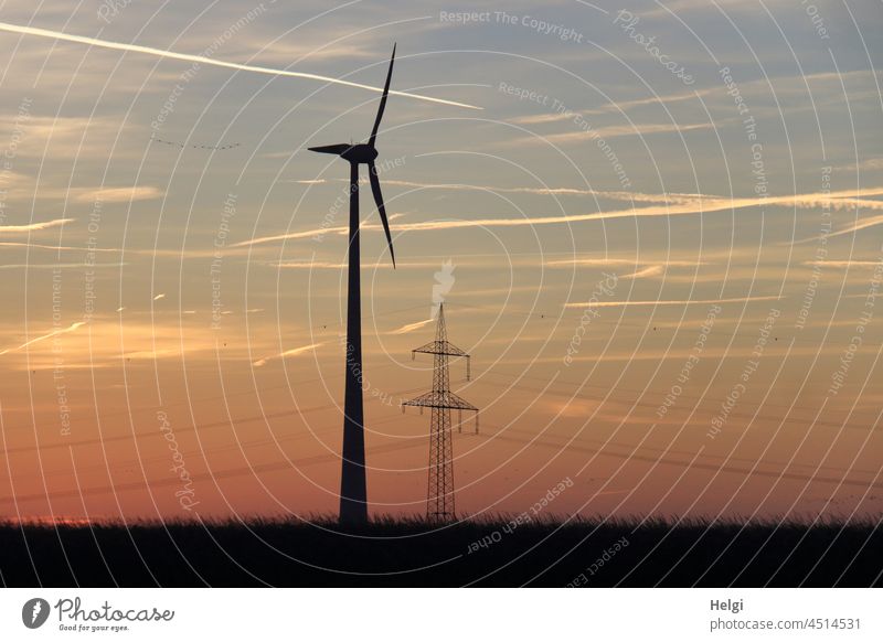 vor Sonnenaufgang - ein Windrad und ein Strommast stehen auf einem Feld , Morgenstimmung vor rötlichem Himmel Windkraftanlage Morgenröte schönes Wetter Energie