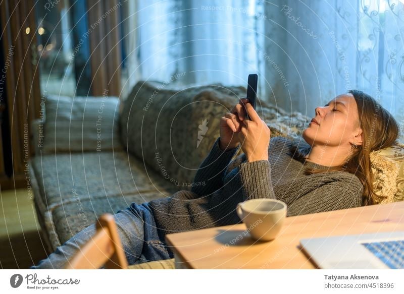 Frau benutzt ihr Telefon auf der Couch Handy heimwärts Smartphone von zu Hause aus arbeiten Internet Liege Mobile Person im Innenbereich Anschluss Lifestyle