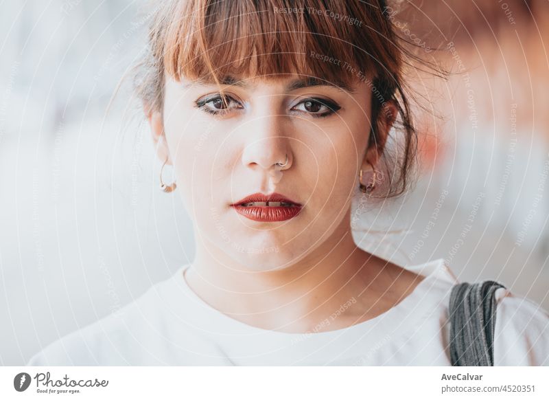 Nahaufnahme einer jungen Frau, die mit ernstem Gesicht und roten Lippen direkt in die Kamera schaut, Make-up auf den Augen, Hipster-Konzeptbild, junge Leute