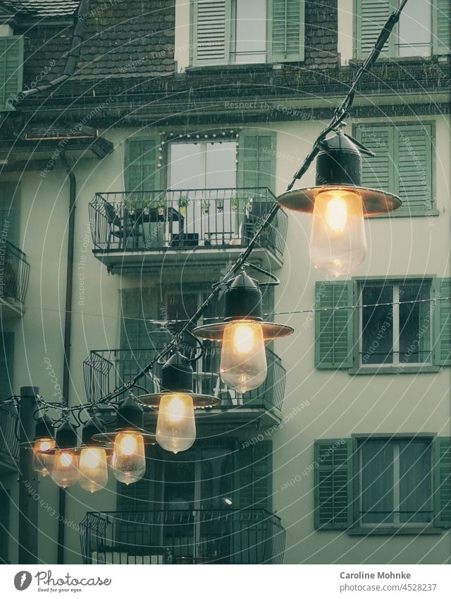 Leuchtende Lampen trotzen dem strömenden Regenwetter Licht Haus Häuser nass schlechtes Wetter Wasser Außenaufnahme Wassertropfen Farbfoto Menschenleer
