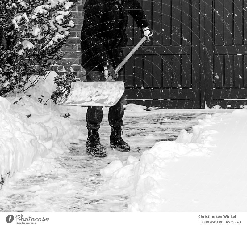 Ein Mann räumt Schnee vor seiner Garage, während es immer noch weiter  schneit - ein lizenzfreies Stock Foto von Photocase