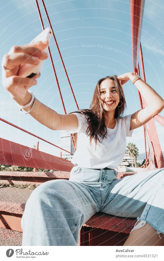 Junge städtische gemischtrassige Frau, die ein Selfie macht, während sie an einem sonnigen Tag lächelt, städtischer Lebensstil, weißes T-Shirt leerer Raum, trendiges soziales Netzwerk, junge Leute, Weitwinkelaufnahme