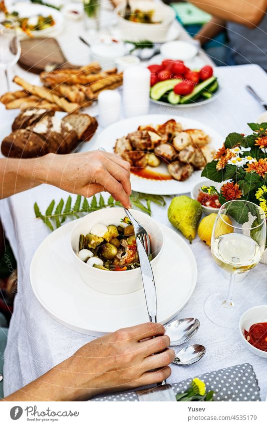 Ein festliches Familienessen oder Barbecue im Sommergarten. Familie Freizeit und Feier und Essen Konzept. Menschen essen bei einer Gartenparty. Grillen, Gemüse, Wein und Snacks. Das Leben in den Vorstädten