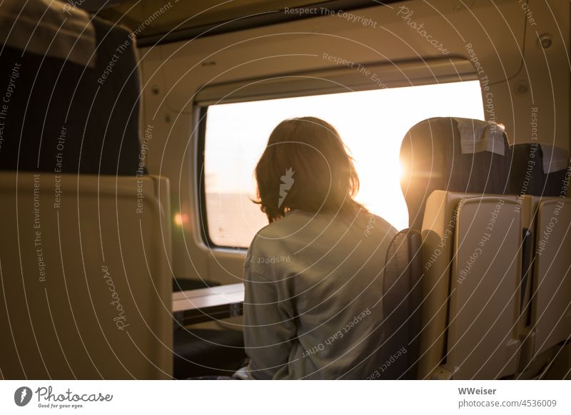 Das Mädchen schaut aus dem Zugfenster in den Sonnenaufgang, unterwegs zu neuen Abenteuern Reise Zugfahrt Fenster Wagen Eisenbahn fahren reisen verreisen Morgen