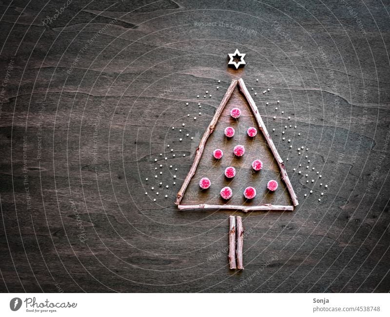 Ein Christbaum aus Ästen und kleinen roten Kugeln auf einem Holztisch Weihnachten Weihnachtsbaum Winter ast kugel verrotten basteln holztisch abstrakt