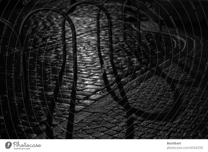 Fahrradständer und Kopfsteinpflaster im Schatten der Nacht Menschenleer Metall Außenaufnahme Schattenspiel Licht Altstadt Kontrast Straße dunkel Stein