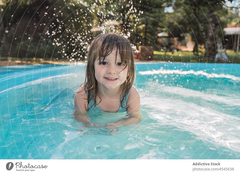 Nettes positives Kind lächelt in die Kamera im Schwimmbad schwimmen Pool Lächeln Urlaub Feiertag Mädchen Hof Glück Sommer Beckenrand Wasser niedlich Kindheit