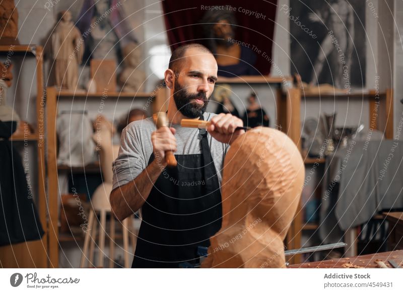 Konzentrierter Handwerker, der mit einem Meißel ein hölzernes Detail formt Zimmerer Beitel Poloschläger Form Holz Tischlerarbeit Werkstatt Handarbeit