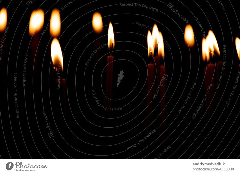 Nahaufnahme einer Menge brennender Kerzen isoliert auf schwarzem Hintergrund. Kerzenschein Flamme Feuer Nacht glühen Kirche Religion Brandwunde Weihnachten