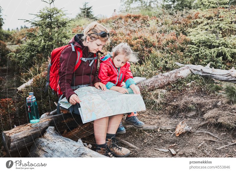 Familienausflug in den Bergen. Mutter und ihre kleine Tochter prüfen eine Karte, sitzen auf einem Baumstumpf während der Reise Kind Ausflug Urlaub Sommer