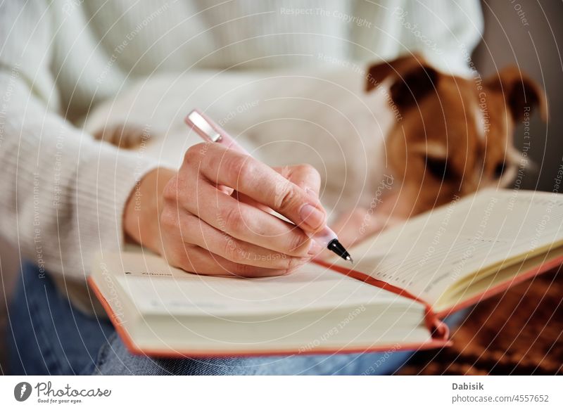 Frau schreibt Notizen in Notizbuch zu Hause Hund Notebook Tagebuch Plan Lifestyle gemütlich heimwärts ruhen sich[Akk] entspannen Büro Arbeitsplatz