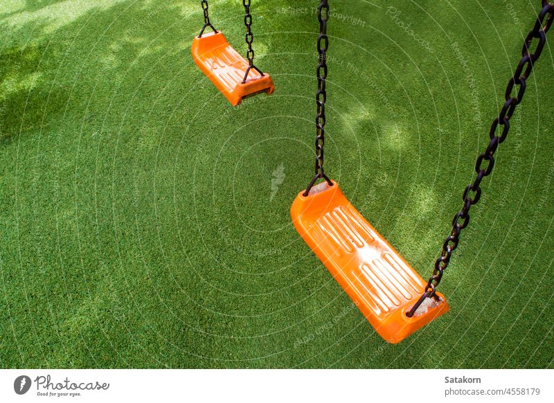 Schaukelsitz auf dem Kunstrasen Spielplatz pendeln Sitz Kind orange Farbe Kunststoff künstlich Gras Park Spaß im Freien spielen Kindheit Schule Erholung
