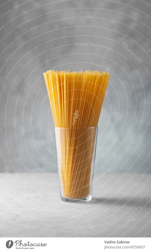Rohe Spaghetti im Glas. Trockene italienische Nudeln aus Hartweizen Spätzle Hintergrund gelb grau Beton Ansicht Essen zubereiten traditionell ungekocht Objekte