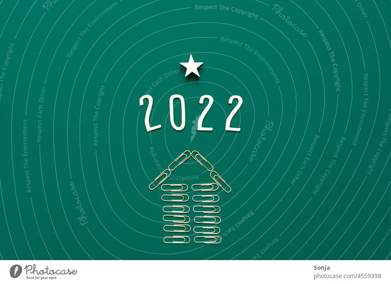 2022 und ein aufsteigender Pfeil aus Büroklammern auf einem grünen Hintergrund. Draufsicht. Erfolg Karriere Zukunft Ziel Richtung richtungweisend vorwärts