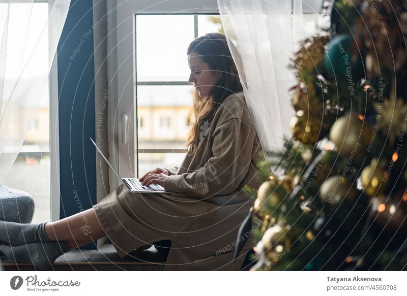Frau benutzt Laptop in Weihnachtsdekoration Weihnachten Lifestyle kaufen online Geschenk Computer Feier heimwärts Dekoration & Verzierung Winter