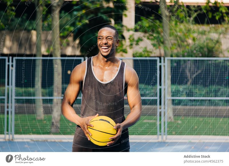 Glücklicher schwarzer Basketballspieler hält Ball Mann Spieler Sport Training Sportler Stadion Sportkleidung Sportpark Motivation selbstbewusst ethnisch