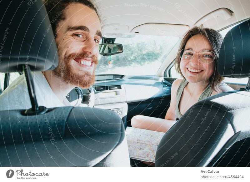Junges Hipster-Paar, das auf einer Autoreise eine Karte benutzt, um sich zu orientieren. Eine Karte lesen. Fröhlich liebendes Paar entspannt im Urlaub. Reise auf Route Urlaub. Glücklich und lächelnd in die Kamera. Entscheidung treffen